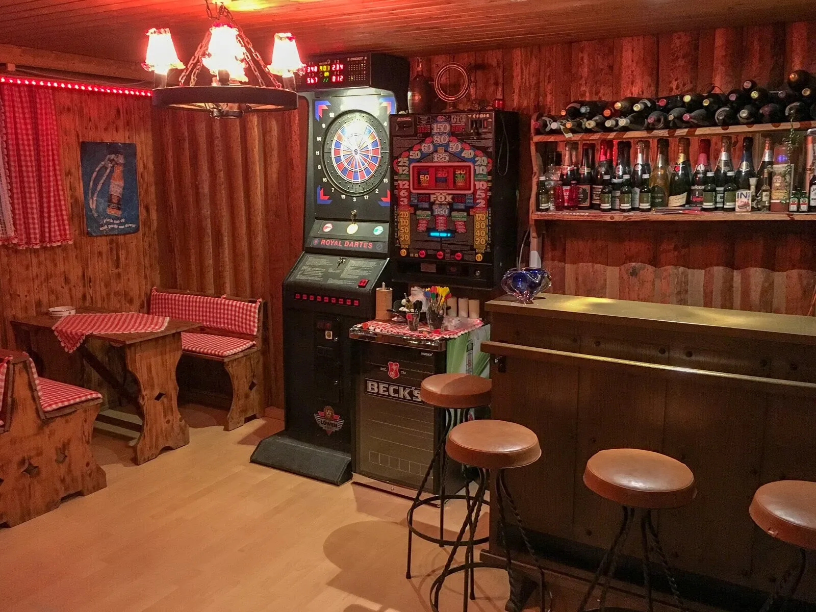 Hausbar mit Dartautomat, Barhockern und rot-weiß karierten Vorhängen